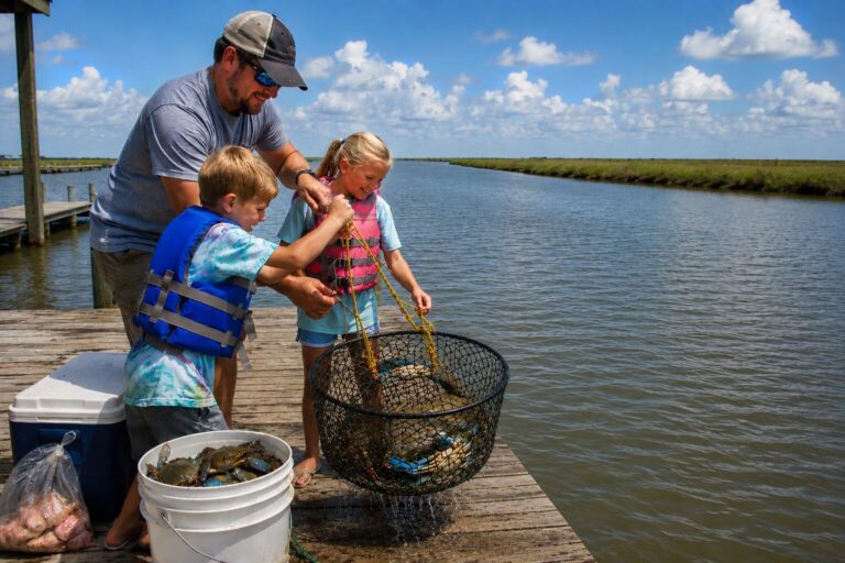 Family pulling a crab trap full of blue crabs from a dock at Bolivar Peninsula on the Texas Gulf Coast